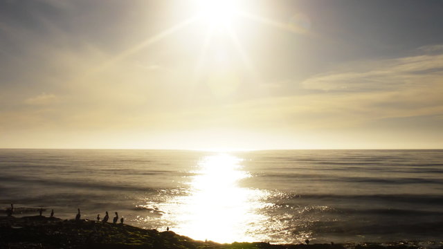  Time lapse footage with tilt up motion of the sun setting into horizon at the ocean in Ocean Beach, San Diego