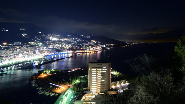  Motion controlled tilt down/pan left time lapse footage with zoom out motion of night cityscape in Atami, Japan
