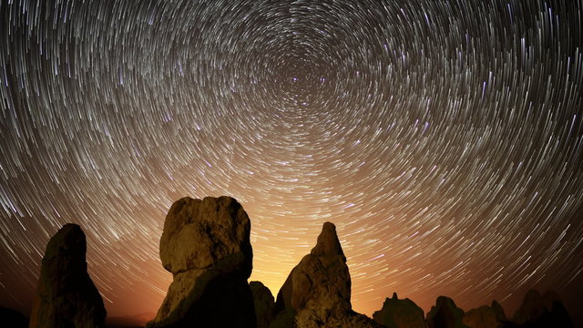  Astrophotography time lapse footage with tilt down motion of star trails over monolithic formations in Trona Pinnacles, California