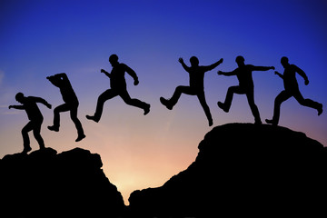 Silhouette of a man jumping over a rock