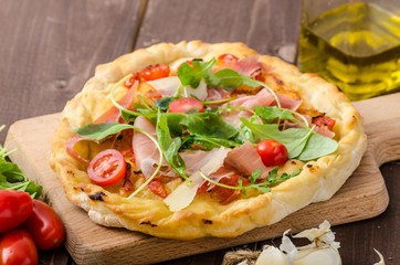 Italian pizza with parmesan cheese, prosciutto and arugula