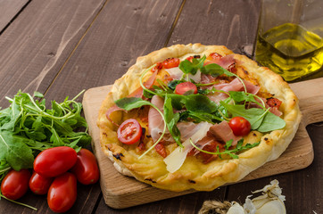 Italian pizza with parmesan cheese, prosciutto and arugula