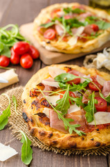 Italian pizza with parmesan cheese, prosciutto and arugula