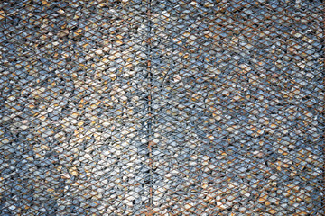 Background made from rusty metal mesh cage and stone