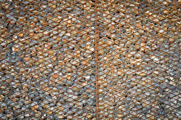 Background made from rusty metal mesh cage and stone