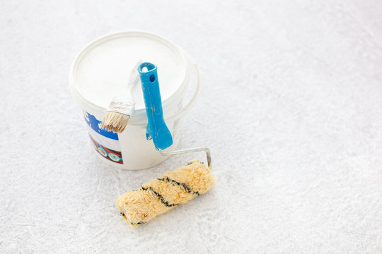 Paint bucket with roller brush on white.