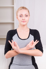 Beautiful  woman practicing yoga at home on the sofa