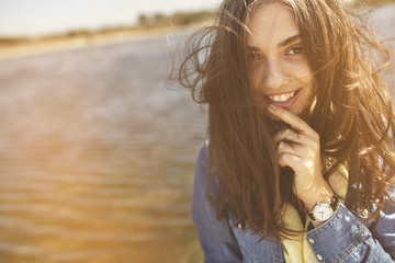 Beautiful sunny portrait of a shy girl holding a finger at mouth