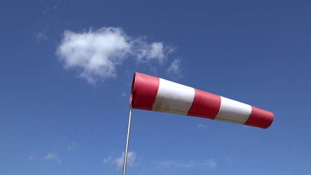Moving air sleeve windsock show direction of wind blowing near helicopter landing place site on background of blue sky. Static shot. 4K UHD video clip.
