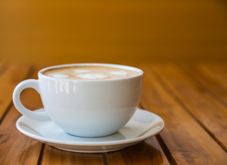 Cup of coffee with heart pattern in a white cup on wood table