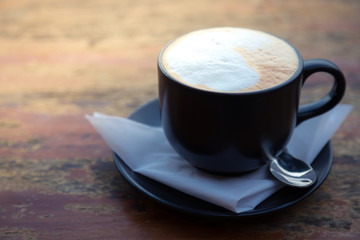 Coffee in black cup on wood table