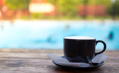Cup of coffee on wooden deck near Swimming pool