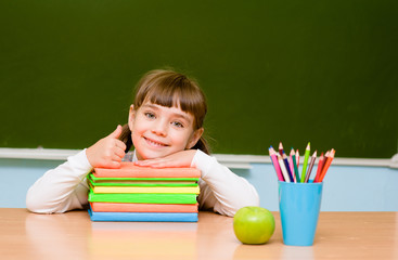 little girl showing thums up on the background of chalkboard