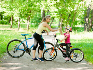 Mom and daughter give high five while cycling in the park