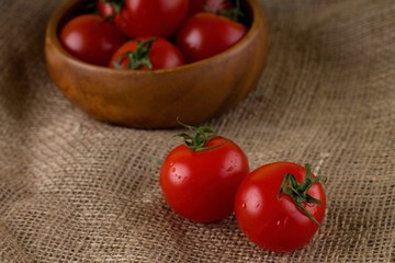Couple of red juicy tomatoes in front of bowl full of others