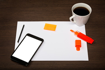 Top view on dark wooden office desk with sheet of paper, mobile with blank screen, pen, highlighter...