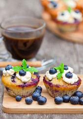 fresh muffins with blueberry and cup of coffee on wooden backgro