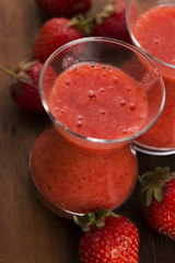 A glass of strawberry smoothie on a wooden background