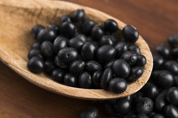 A lot of black soybeans on wooden background