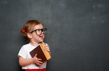 happy  girl schoolgirl with book from blackboard