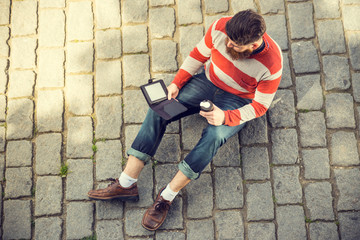 Fototapeta na wymiar Trendy hipster young man reading digital book