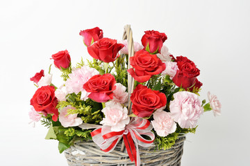 red roses and pink carnations in a basket