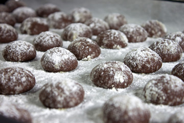 Cracked chocolate cookies with icing sugar on a pan