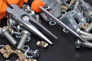 Fototapeta premium Construction tools and bolts on black metal surface 