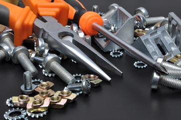 Construction tools and bolts on black metal surface