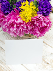 bouquet of flowers and a blank sheet of paper on wooden planks