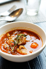Pork stew in white bowl on wooden table