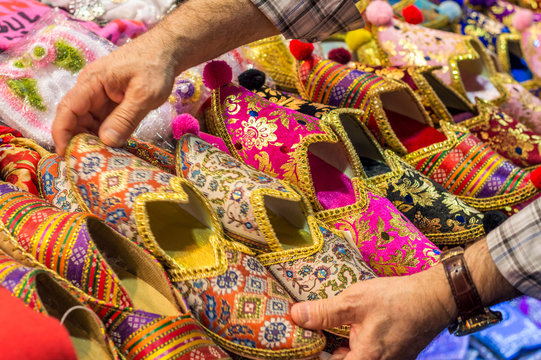 Colorful turkish slippers and shoes for sale on bazaar market, with hand movement of a buyer