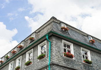 Alte Fassade mit Schieferplatten und Blumen