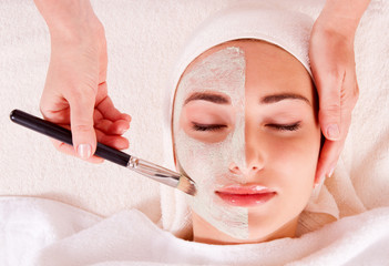 Face of beautiful woman with facial mask at spa salon.