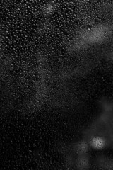 Raindrops on glass, black and white background, selective focus
