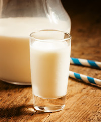 Fresh peasant milk jug and glasses on old wooden table, selectiv