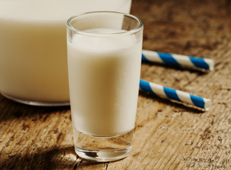 Fresh peasant milk jug and glasses on old wooden table, selectiv