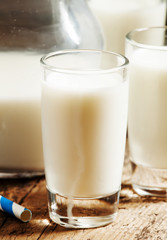 Fresh peasant milk jug and glasses on old wooden table, selectiv