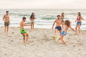 Group of friends playing with ball on the beach