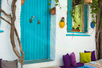 Flowerpots hanged on the  colorful walls and windows of the beautiful old houses in Bozcaada