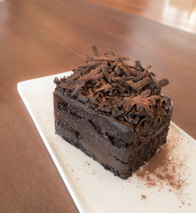 Chocolate cake in white plate on wooden background