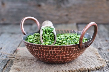 Fototapeta na wymiar Dried green split peas in a copper plate on a wooden table