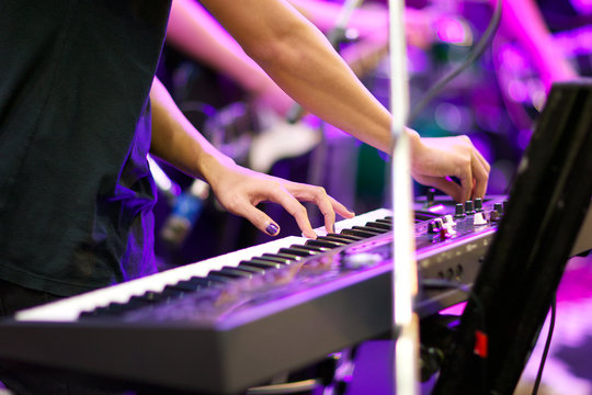hands of musician playing keyboard in concert with shallow depth of field, focus on left hand