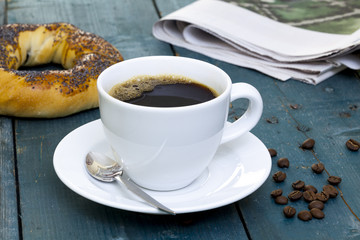 Cup of coffee with bagel and newspaper