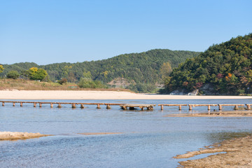 Fototapeta na wymiar single lane log bridge over a shallow river