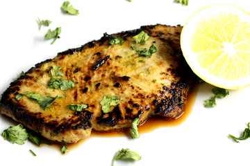 served delicious piece of tuna steak with greenery and lemon
