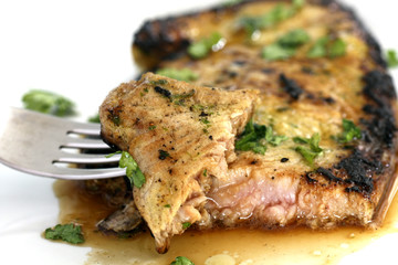served delicious piece of tuna steak with greenery and dinnerware
