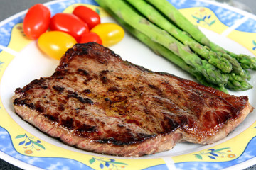 served delicious piece of medium grilled beef steak with tomatos and asparagus
