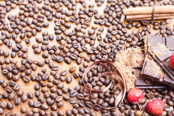 For holiday of chocolate day - wooden table background decorated a lot of coffee beans, chocolate bar, cacao, strawberries, cinnamon. Selective focus