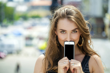 Fototapeta na wymiar Young blonde woman covers her face screen smartphone